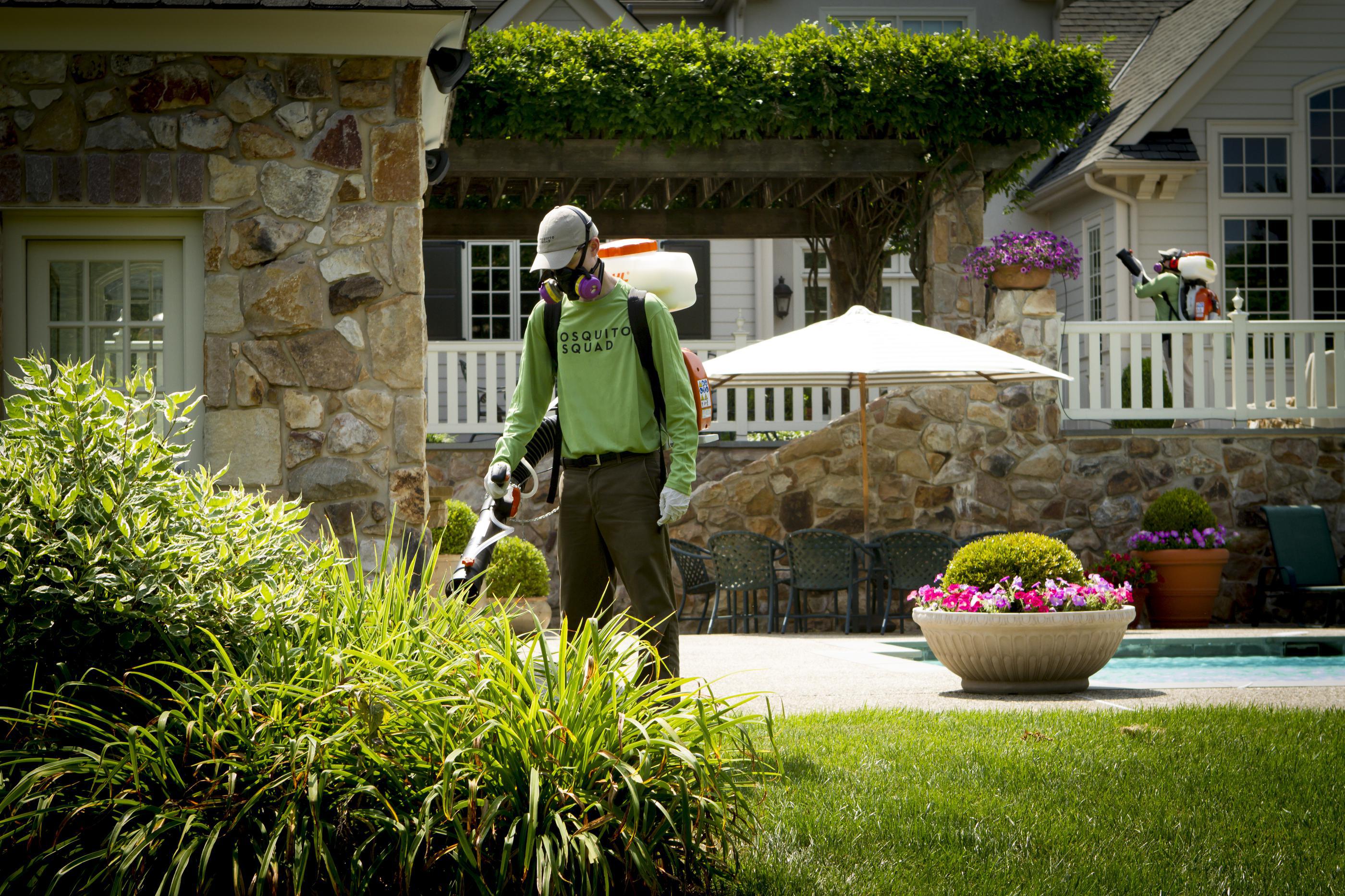 A person wearing a green shirt and a hat and holding a lawn mowerDescription automatically generated