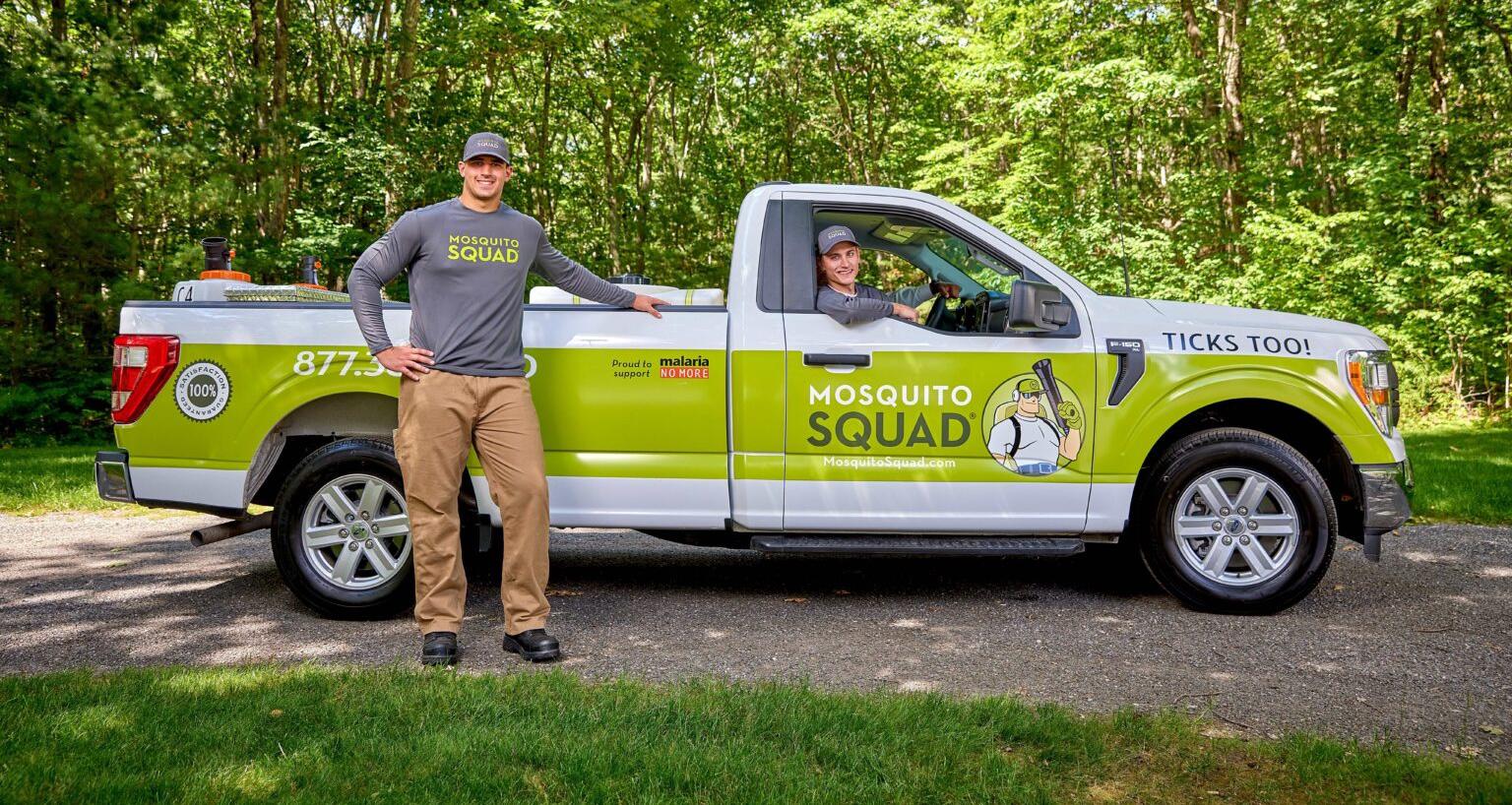 Two Mosquito Squad employees- one standing outside their work truck, and one driving it.