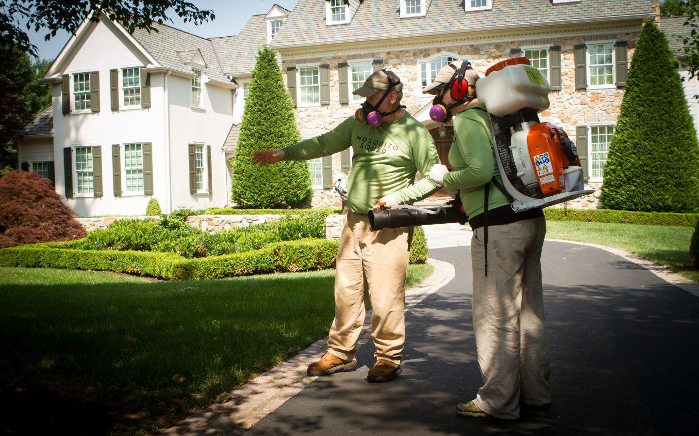 A person and person wearing masks and standing on a drivewayDescription automatically generated